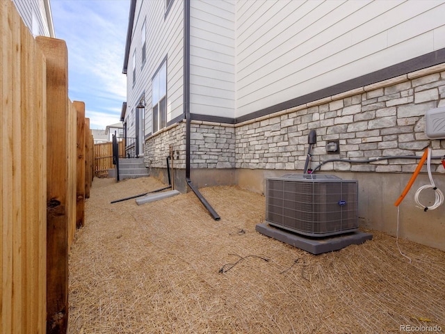 view of property exterior with fence, cooling unit, and stone siding