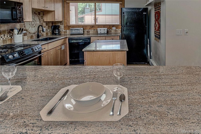 kitchen featuring a center island, black appliances, sink, decorative backsplash, and light stone countertops