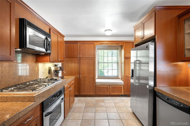 628 Cherry St, Denver, CO 80220 - kitchen featuring stainless steel appliances, brown cabinets, and tasteful backsplash