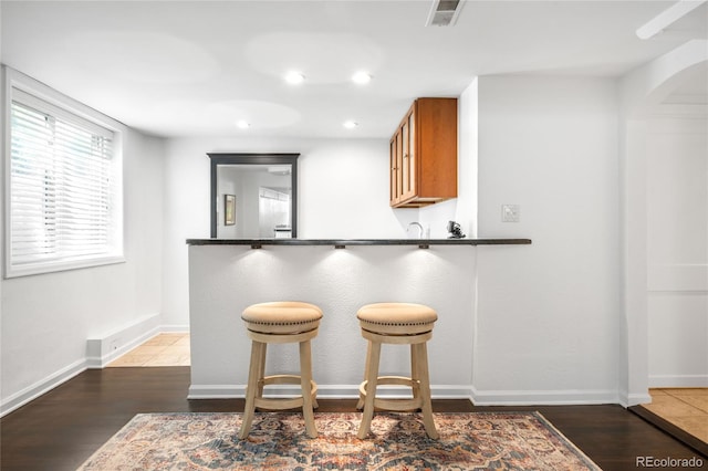 628 Cherry St, Denver, CO 80220 - kitchen featuring brown cabinetry, dark countertops, a breakfast bar area, wood finished floors, and recessed lighting