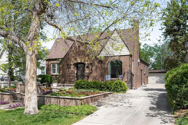 628 Cherry St, Denver, CO 80220 - tudor-style house with brick siding, an outdoor structure, a chimney, and a detached garage