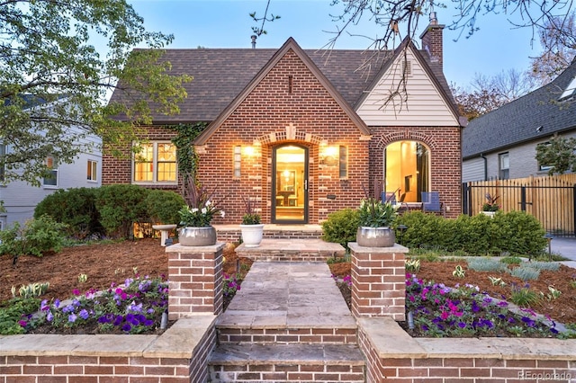 628 Cherry St, Denver, CO 80220 - tudor house with brick siding, fence, a chimney, and roof with shingles