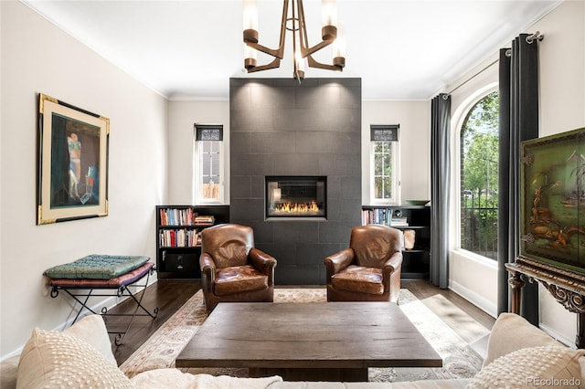 628 Cherry St, Denver, CO 80220 - living room featuring wood finished floors, ornamental molding, a tile fireplace, baseboards, and a chandelier
