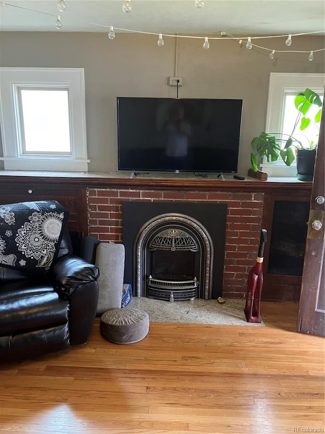 living room with a brick fireplace and hardwood / wood-style floors