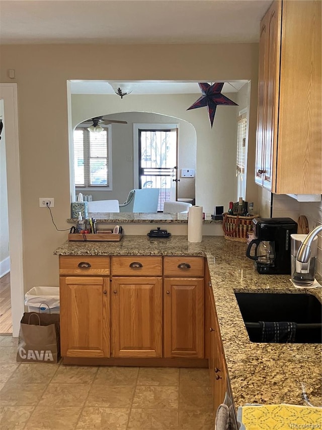 kitchen with sink, light stone countertops, ceiling fan, and light tile floors