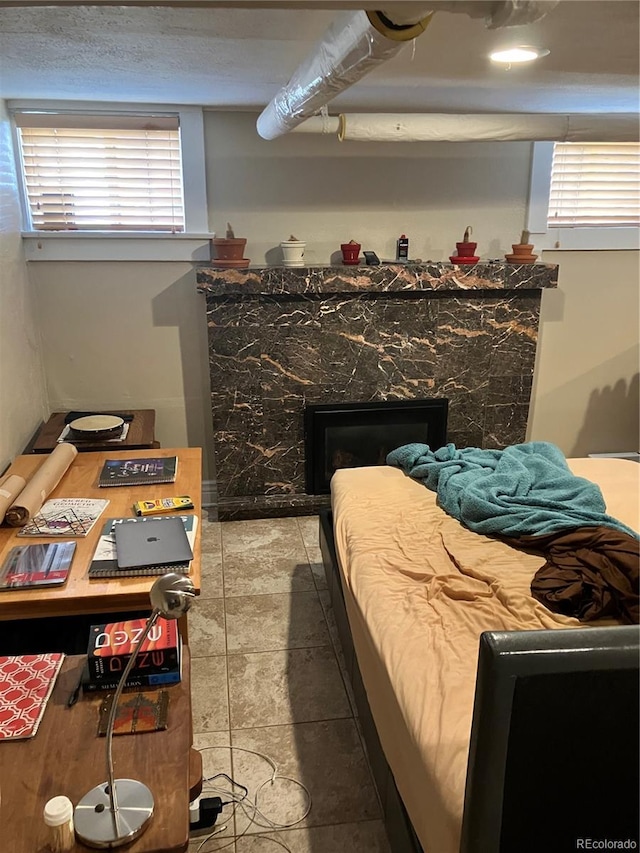 bedroom featuring a high end fireplace, multiple windows, and light tile flooring