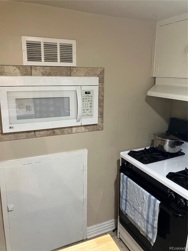 kitchen with wall chimney range hood, white appliances, and light wood-type flooring