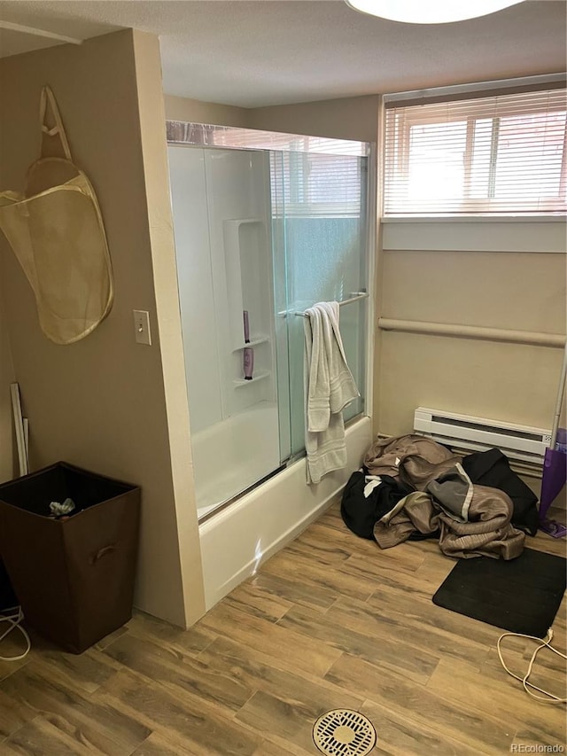 bathroom featuring a baseboard radiator, combined bath / shower with glass door, and wood-type flooring