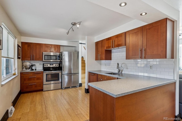 kitchen featuring stainless steel appliances, tasteful backsplash, sink, and light wood-type flooring