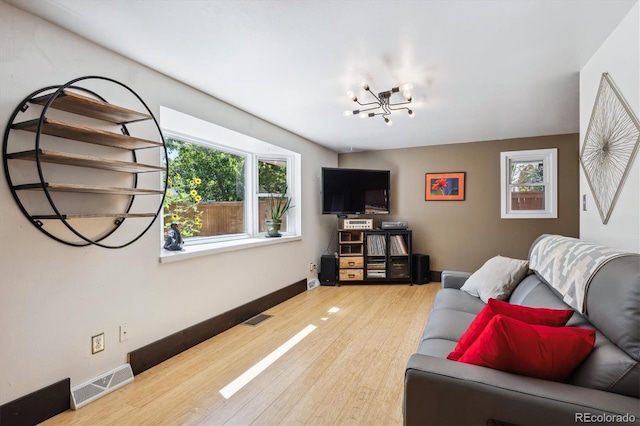 living room with wood-type flooring, a wealth of natural light, and an inviting chandelier