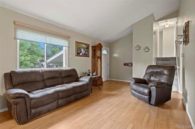 living area with light wood-style flooring, baseboards, and vaulted ceiling