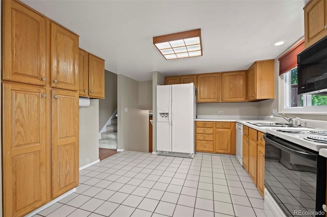 kitchen with baseboards, light countertops, light tile patterned floors, white appliances, and a sink