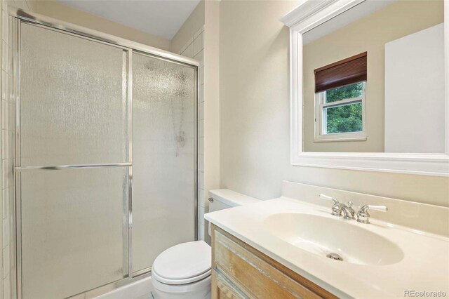 bathroom with vanity, toilet, and a shower stall