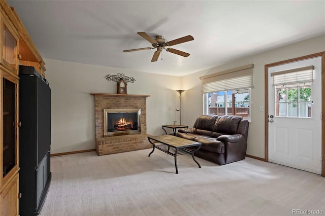 living area with a ceiling fan, baseboards, light colored carpet, and a fireplace