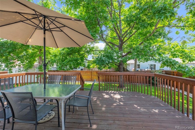 wooden terrace featuring outdoor dining area, a lawn, and a fenced backyard