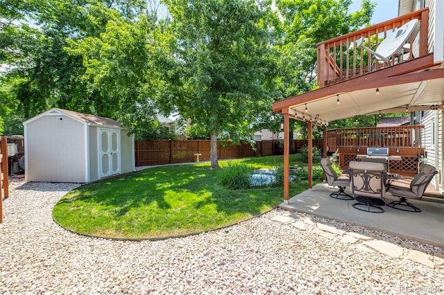 view of yard featuring a wooden deck, a storage shed, a fenced backyard, an outdoor structure, and a patio