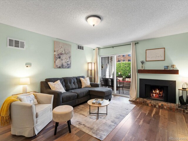 living area featuring visible vents, wood-type flooring, and a brick fireplace