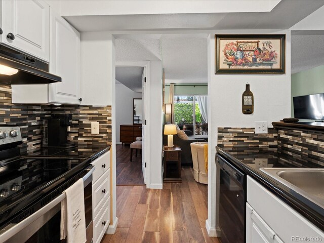 kitchen featuring electric range, under cabinet range hood, black dishwasher, dark countertops, and backsplash