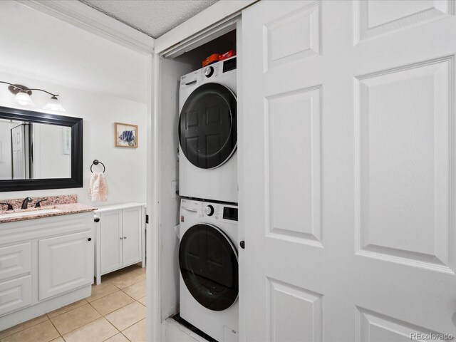laundry room with stacked washer / drying machine and light tile patterned flooring