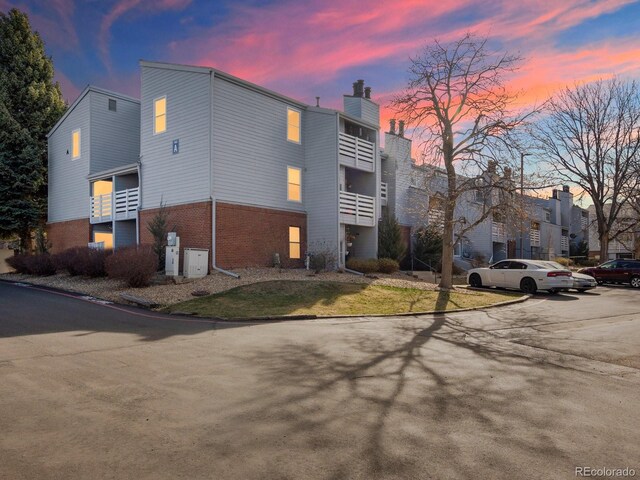 view of side of property with brick siding, a chimney, and uncovered parking