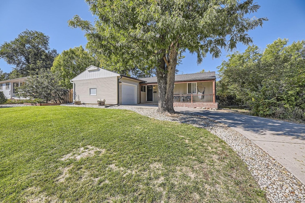 view of front of home with a garage, covered porch, and a front lawn