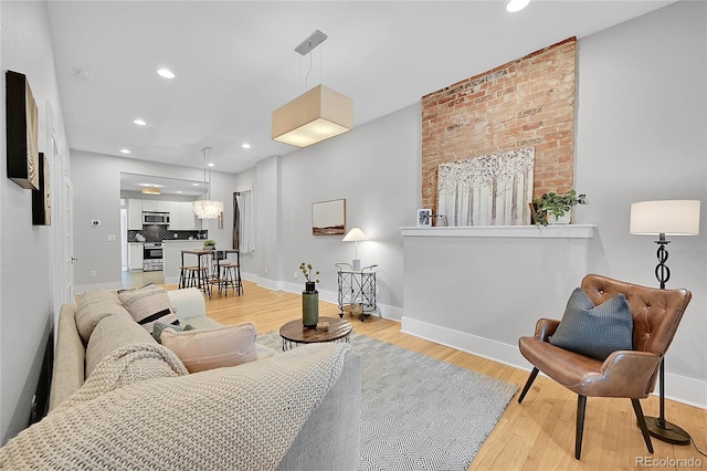 living room with light hardwood / wood-style floors and brick wall