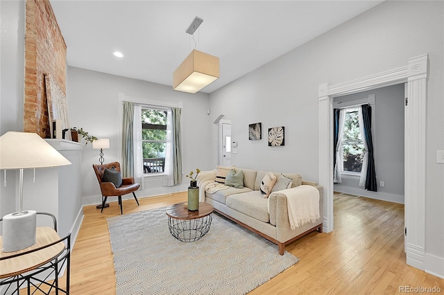 living room with light hardwood / wood-style floors and brick wall