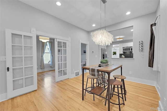 dining area featuring light hardwood / wood-style floors, a chandelier, and french doors