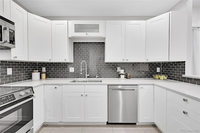 kitchen with appliances with stainless steel finishes, sink, backsplash, and white cabinets