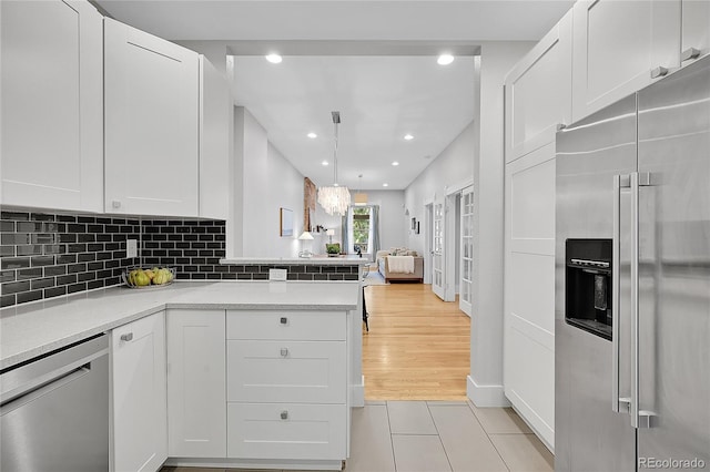 kitchen featuring white cabinetry, backsplash, stainless steel appliances, and light hardwood / wood-style flooring