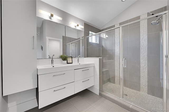 bathroom featuring a shower with shower door, vaulted ceiling, vanity, and tile patterned floors