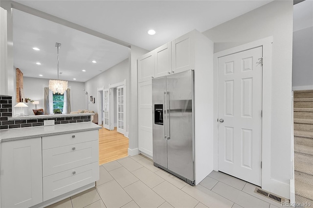 kitchen with light wood-type flooring, tasteful backsplash, white cabinetry, pendant lighting, and high end fridge