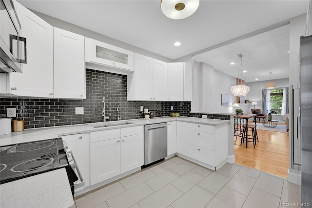 kitchen featuring sink, white cabinetry, tasteful backsplash, dishwasher, and light tile patterned floors