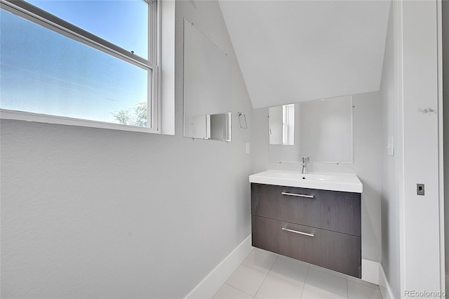 bathroom with tile patterned floors, vaulted ceiling, and vanity