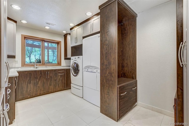 washroom with cabinets, independent washer and dryer, a textured ceiling, and sink