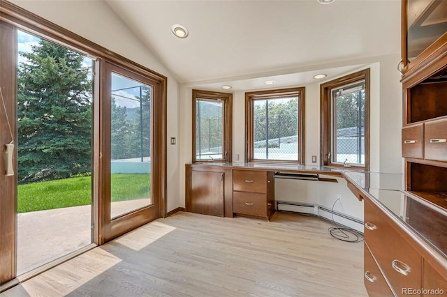 doorway featuring light wood-type flooring, vaulted ceiling, and plenty of natural light