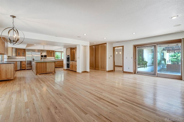 kitchen featuring light wood-type flooring, stainless steel appliances, pendant lighting, a notable chandelier, and a center island