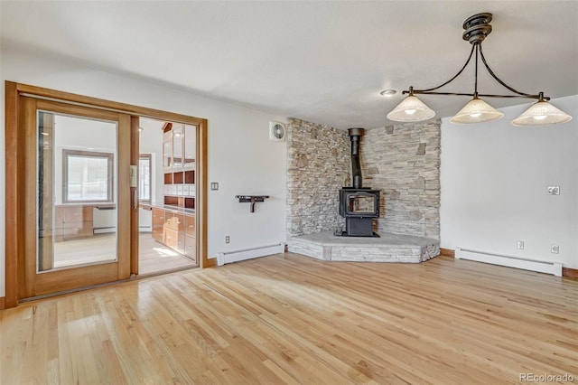 unfurnished living room with baseboard heating, a wood stove, and hardwood / wood-style floors