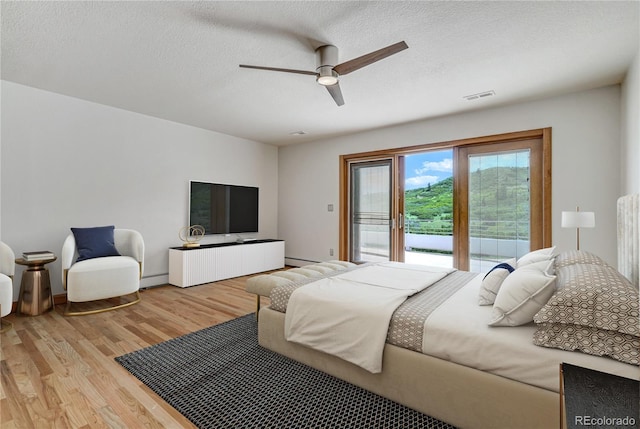 bedroom with access to exterior, a textured ceiling, light wood-type flooring, and ceiling fan