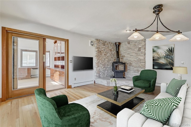 living room featuring wood-type flooring, a wood stove, and a baseboard heating unit