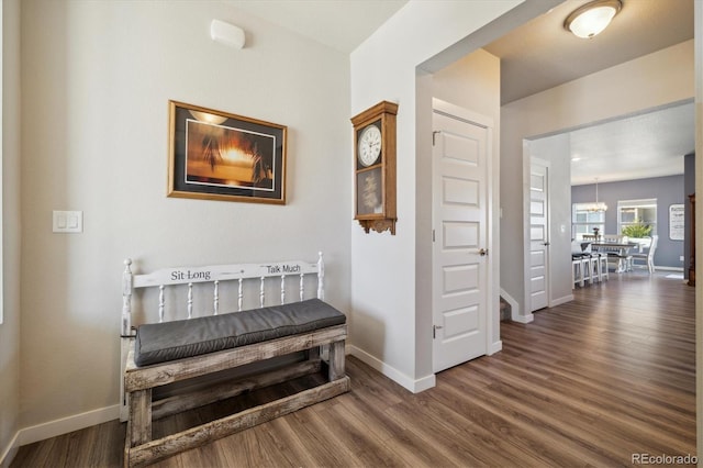 hallway with an inviting chandelier, baseboards, and wood finished floors