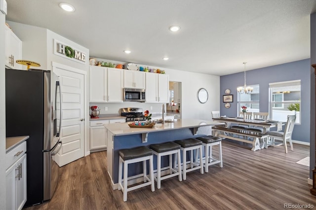 kitchen featuring a breakfast bar, stainless steel appliances, a notable chandelier, white cabinets, and dark wood-type flooring