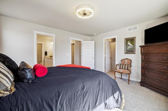 bedroom featuring baseboards, light carpet, ensuite bath, and visible vents