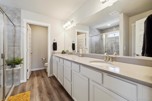 full bath with double vanity, toilet, a sink, visible vents, and a shower stall