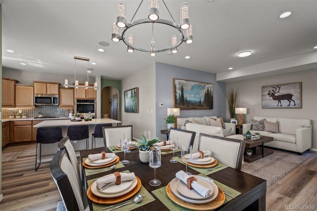 9389 Mayflower Gulch Way, Colorado Springs, CO 80927 - dining space with arched walkways, a chandelier, recessed lighting, and light wood-style floors