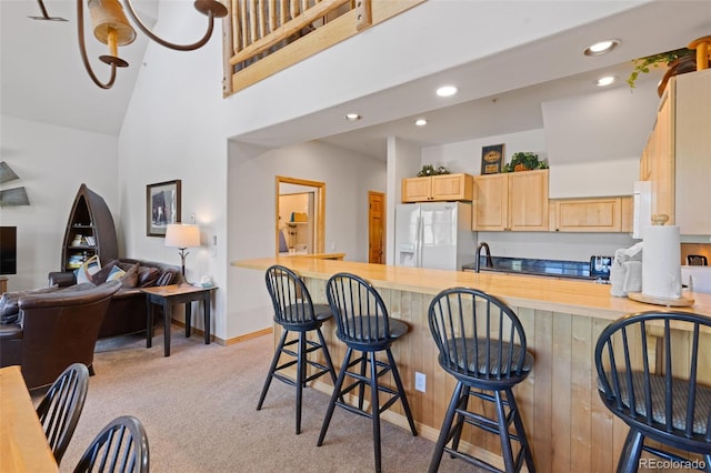 33 Broken Lance Dr Unit 207S, Breckenridge, CO 80424 - kitchen featuring white fridge with ice dispenser, light brown cabinetry, light carpet, recessed lighting, and a high ceiling