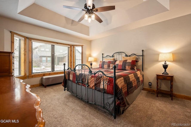 carpeted bedroom featuring a raised ceiling and ceiling fan