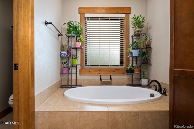 bathroom with tiled tub and toilet