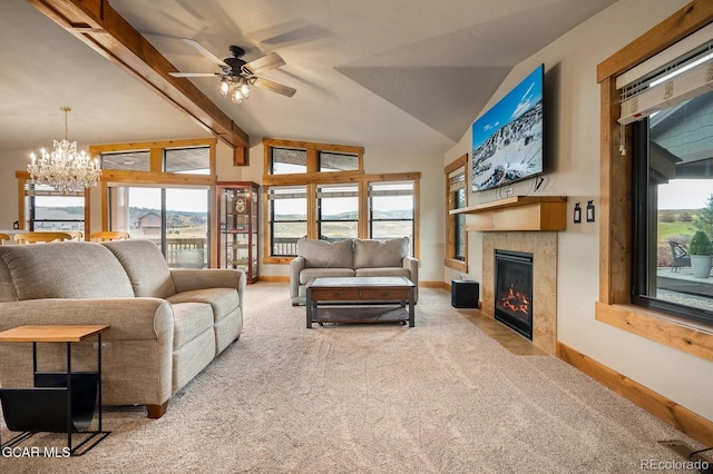 carpeted living room featuring a tiled fireplace, ceiling fan with notable chandelier, and lofted ceiling