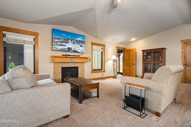 carpeted living room with ceiling fan, lofted ceiling, and a tiled fireplace